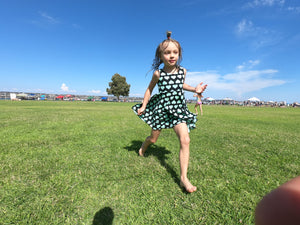 Young girl running in grass with custom dress with heart pattern